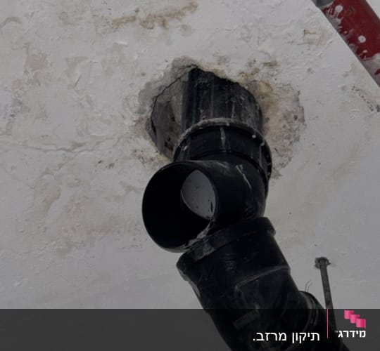 צינור שחור מותקן בתקרה עם סימני רטיבות